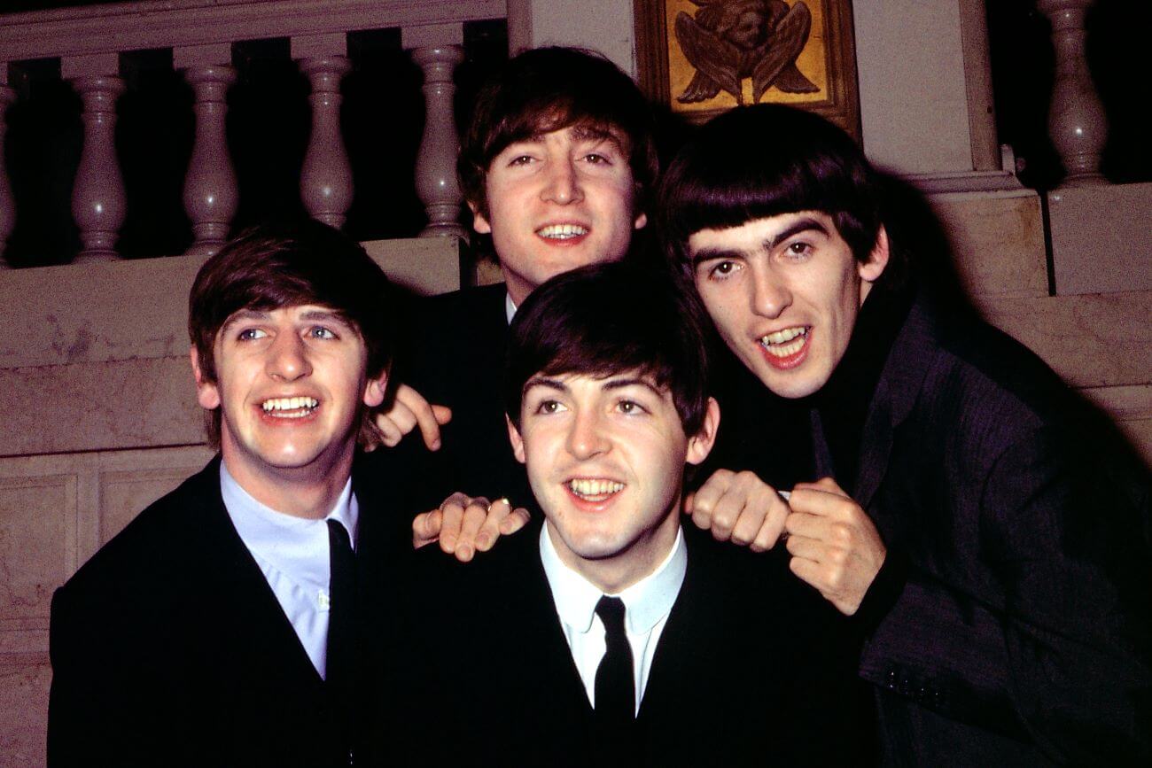 Ringo Starr, John Lennon, Paul McCartney, and George Harrison pose together under a bannister.