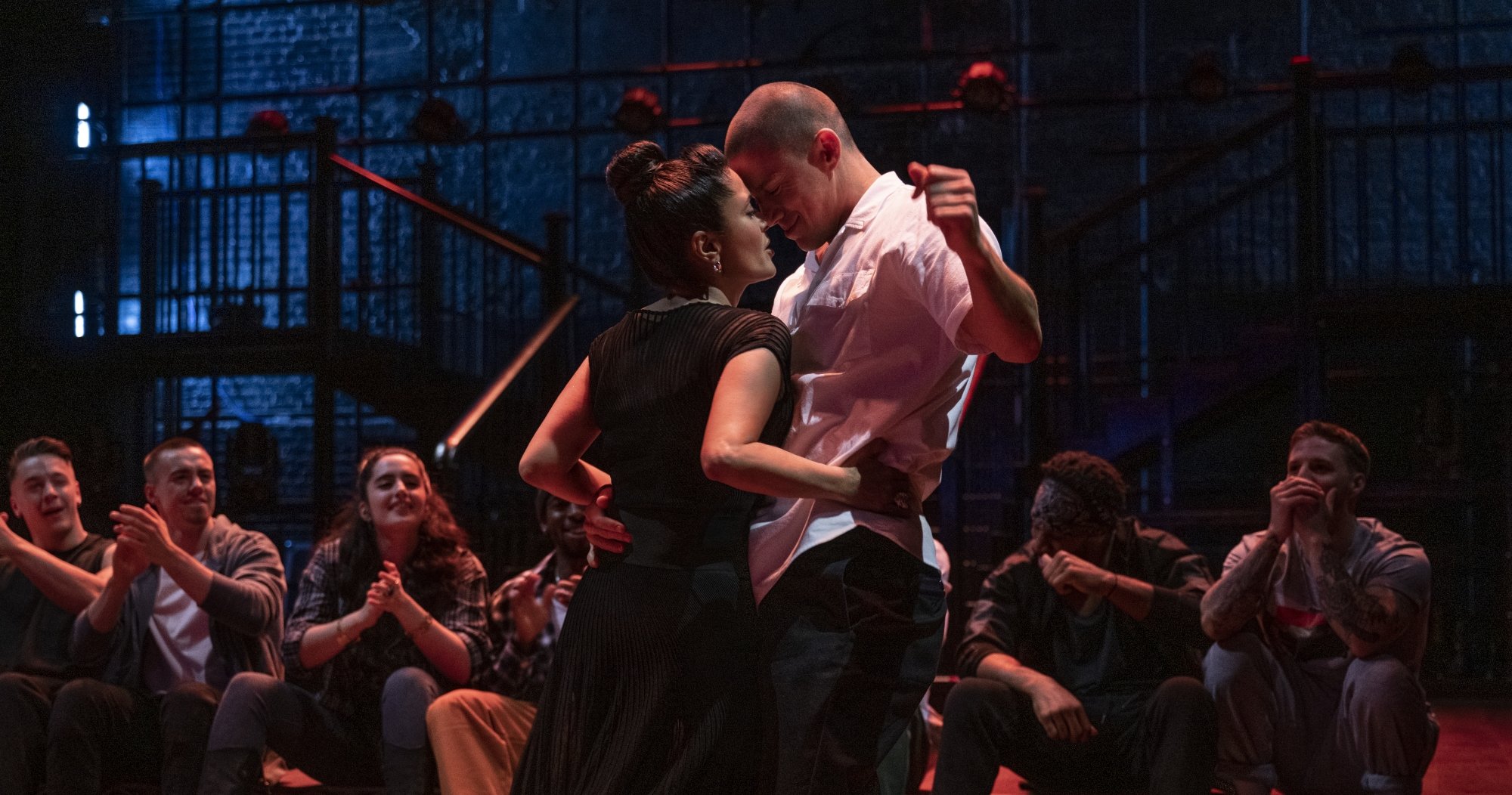 'Magic Mike's Last Dance' Salma Hayek as Maxandra Mendoza and Channing Tatum as Mike Lane. They are smiling, dancing up against each other in front of a line of people, who are clapping.