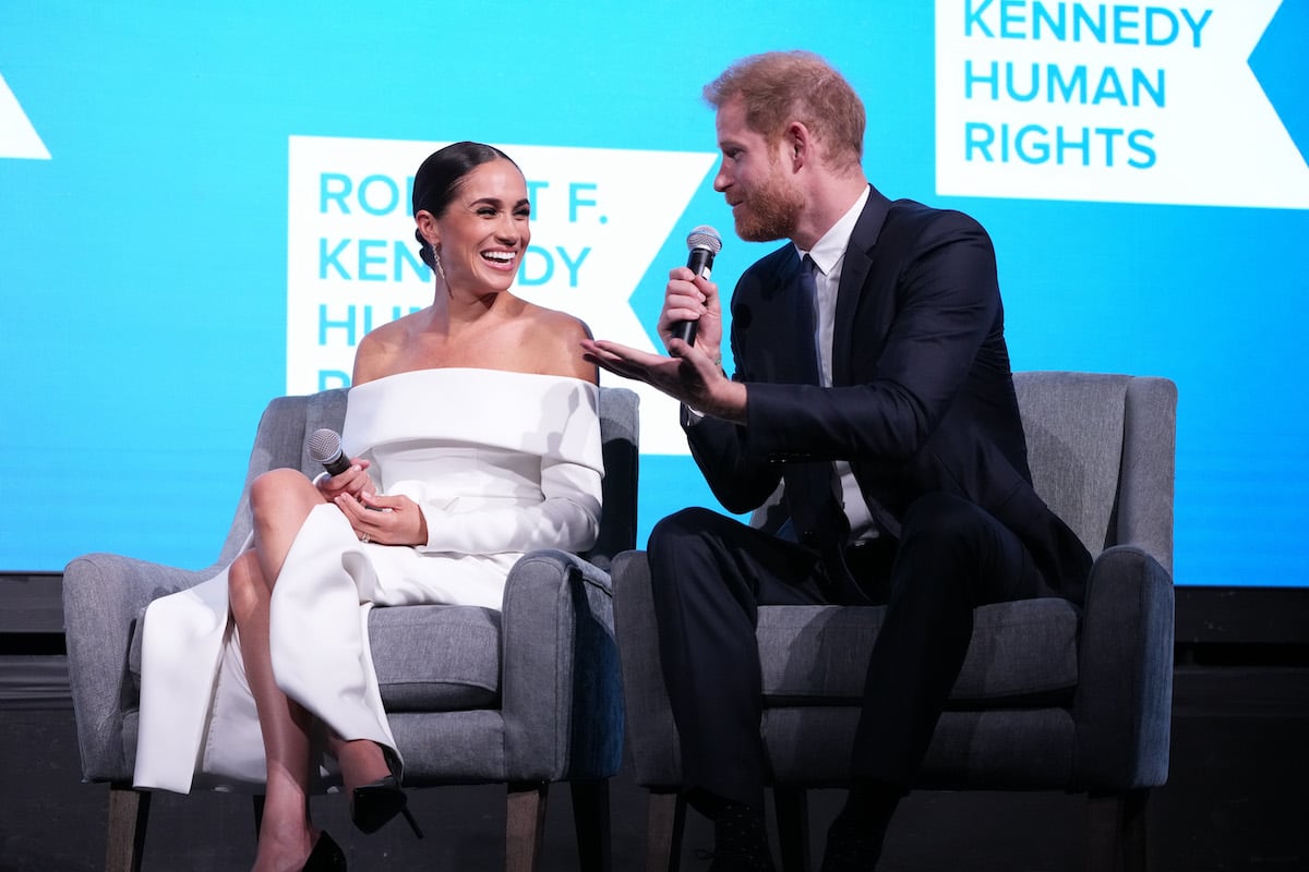 Meghan Markle and Prince Harry, whose Archewell Foundation impact report suggested what's next, smile sitting onstage