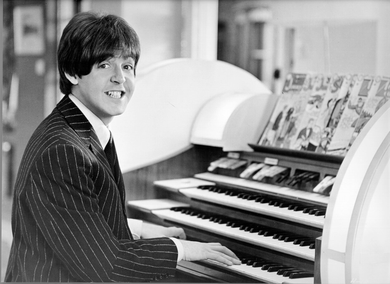 The Beatles' Paul McCartney smiles for the camera as he sits at an organ in a photo taken circa 1965.