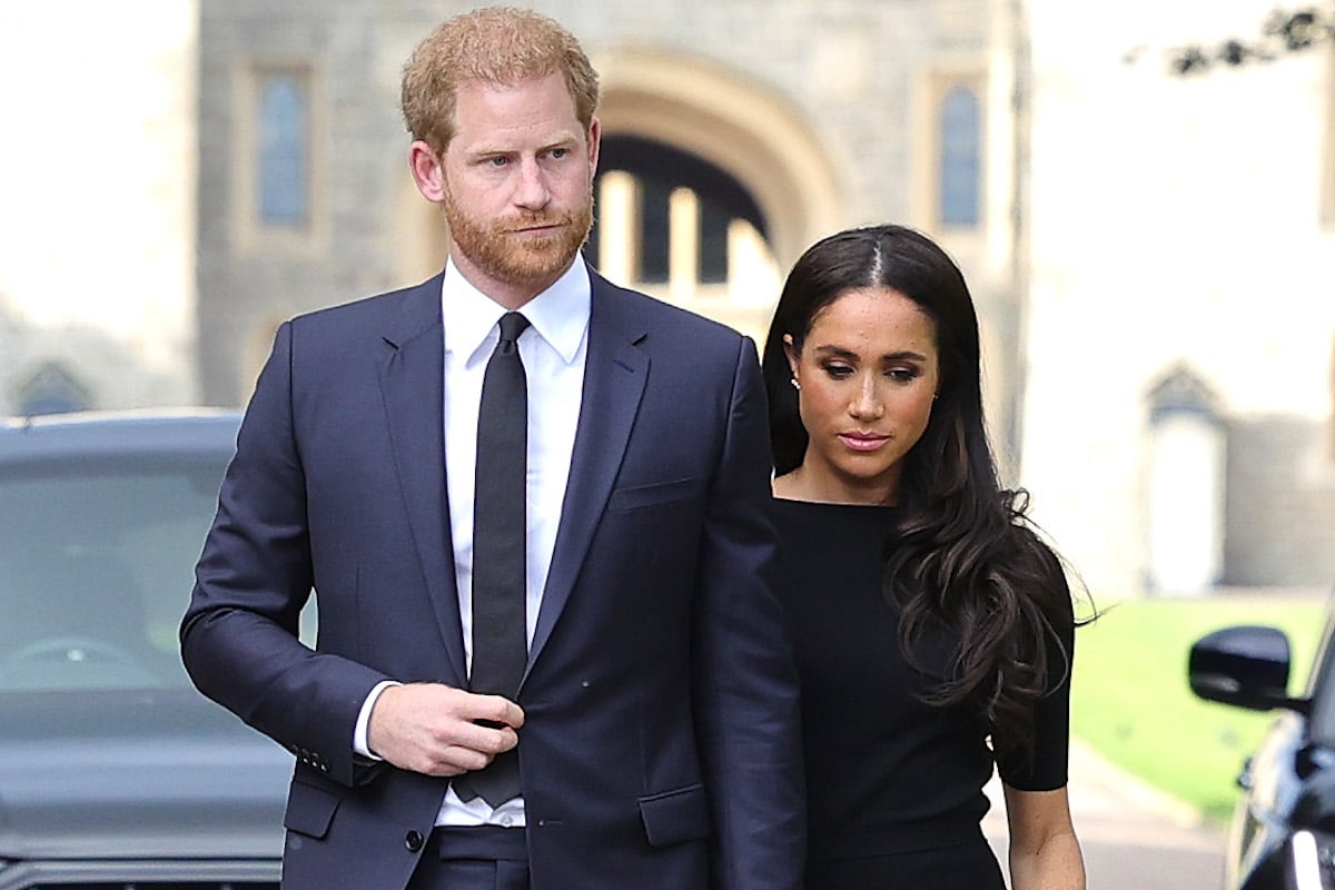 Prince Harry, whom a commentator says King Charles and Prince William are 'working in tandem' to try to get him to attend the coronation, stands with Meghan Markle