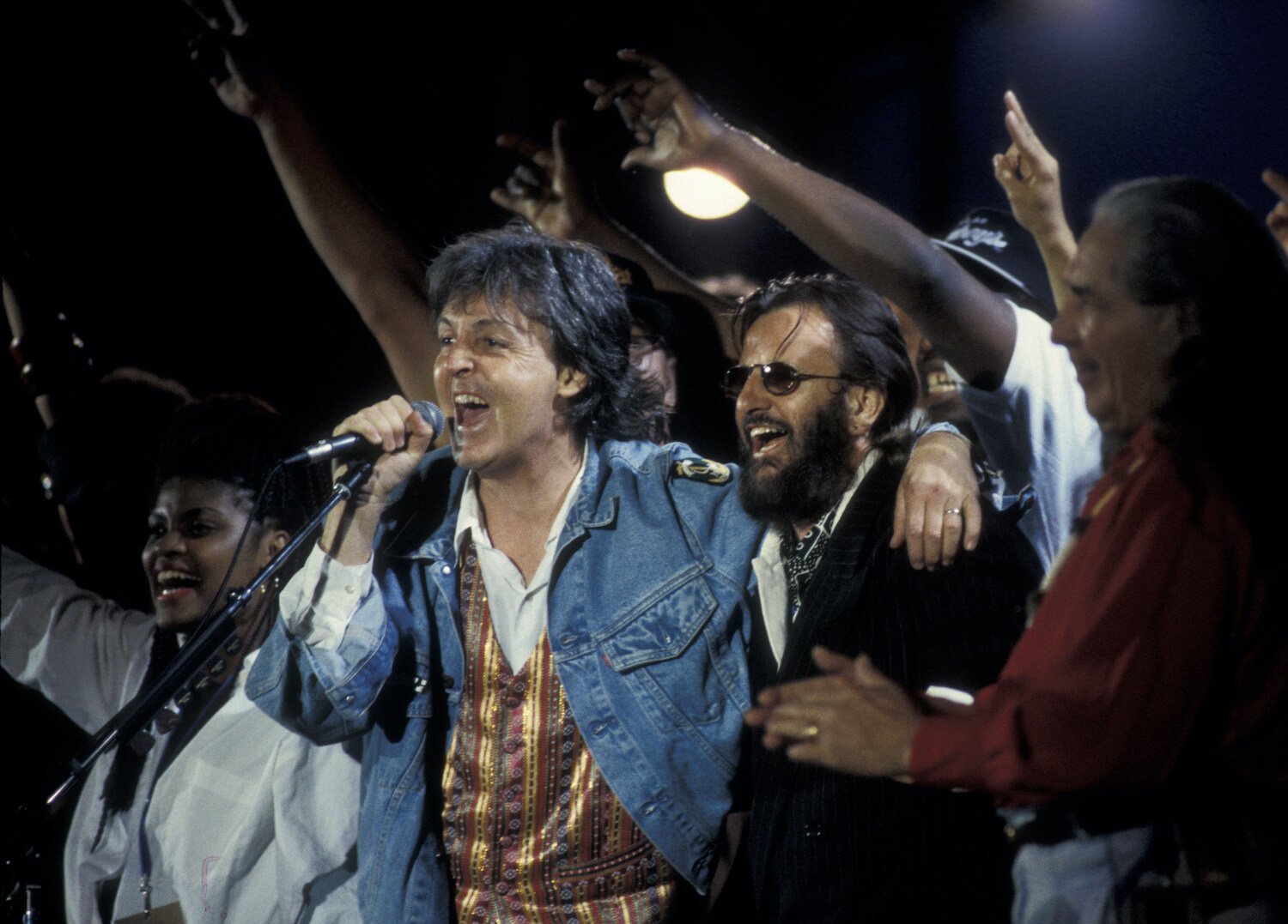 Paul McCartney (left) takes the microphone as he stands next to Ringo Starr at the 1993 Sound Action Earth Day concert.