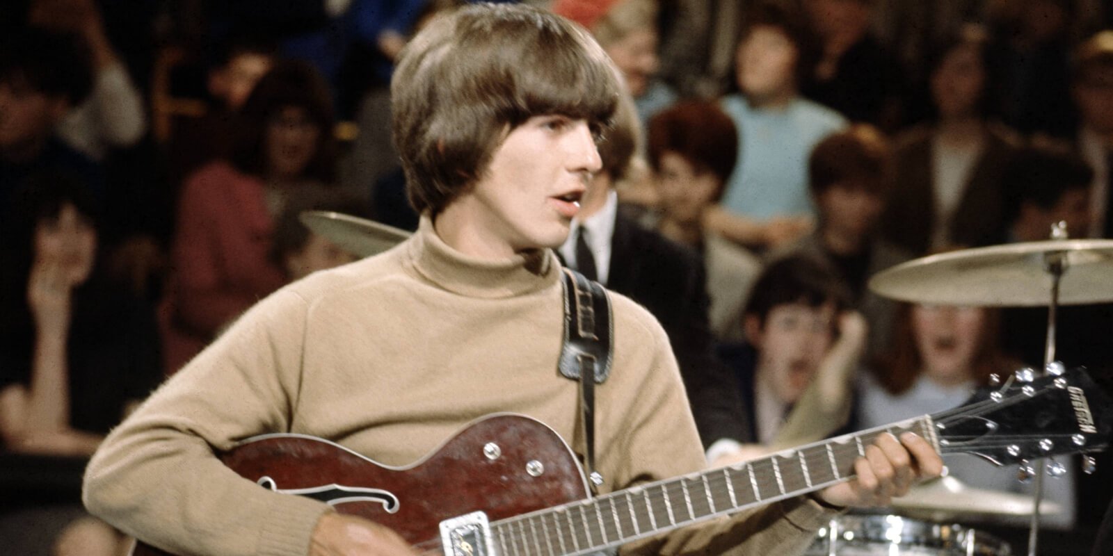 George Harrison playing songs on a guitar