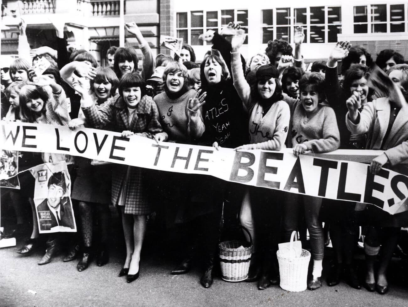 A black and white picture of Beatles fans holding a sign that says "We Love The Beatles."