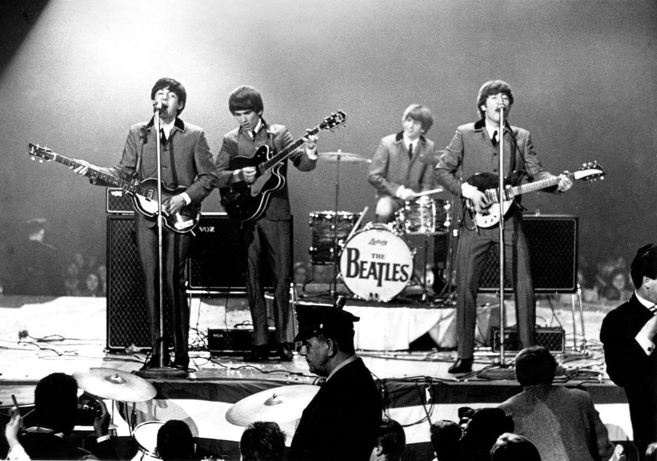 A black and white picture of Paul McCartney, George Harrison, Ringo Starr, and John Lennon performing on stage.