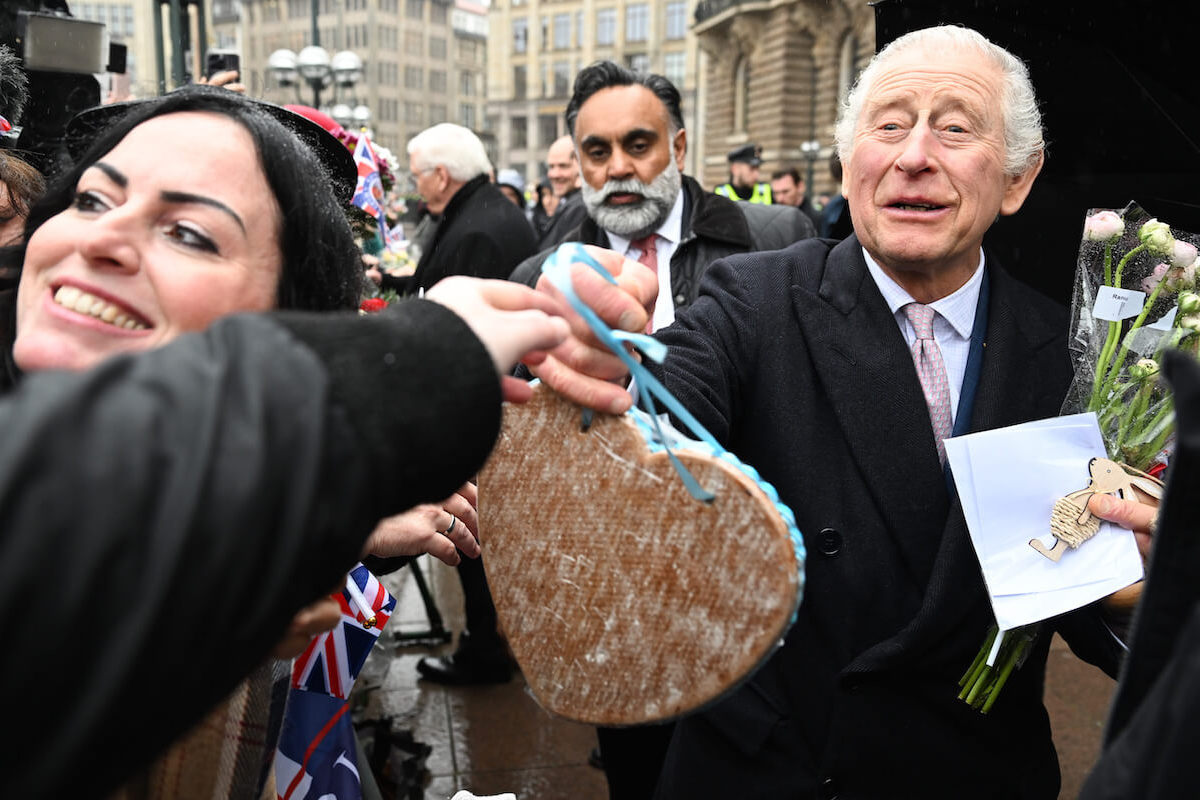 King Charles, whose 'gesture' of picking up a man's hat in Berlin, Germany, would've had Princess Diana, Kate Middleton, and Meghan Markle getting headlines, according to a body language expert, greets crowds