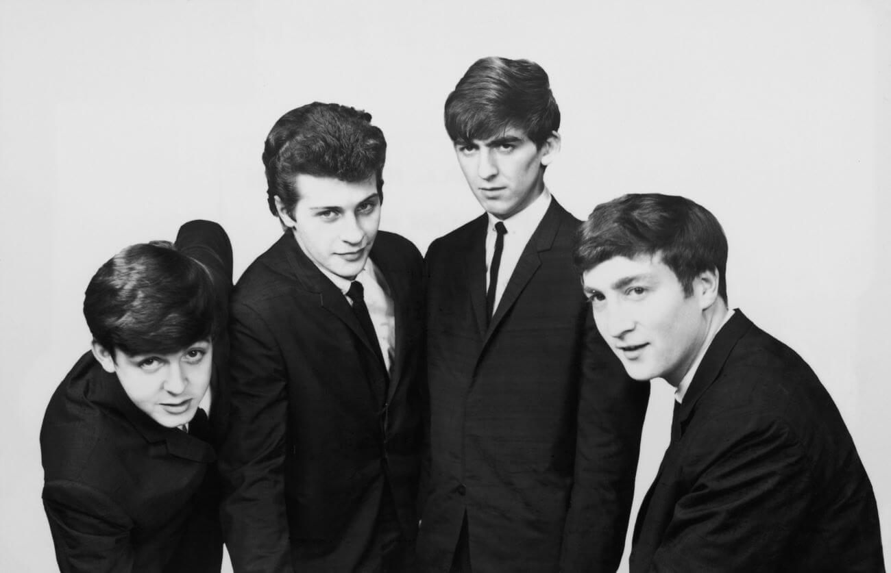 A black and white picture of Paul McCartney, Pete Best, George Harrison, and John Lennon of The Beatle wearing suits.