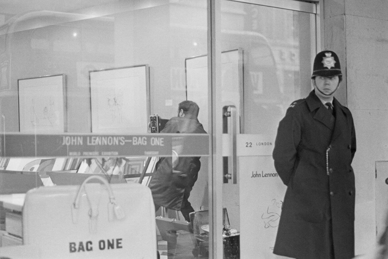 A black and white picture of a police officer standing in front of the Bag One exhibit.