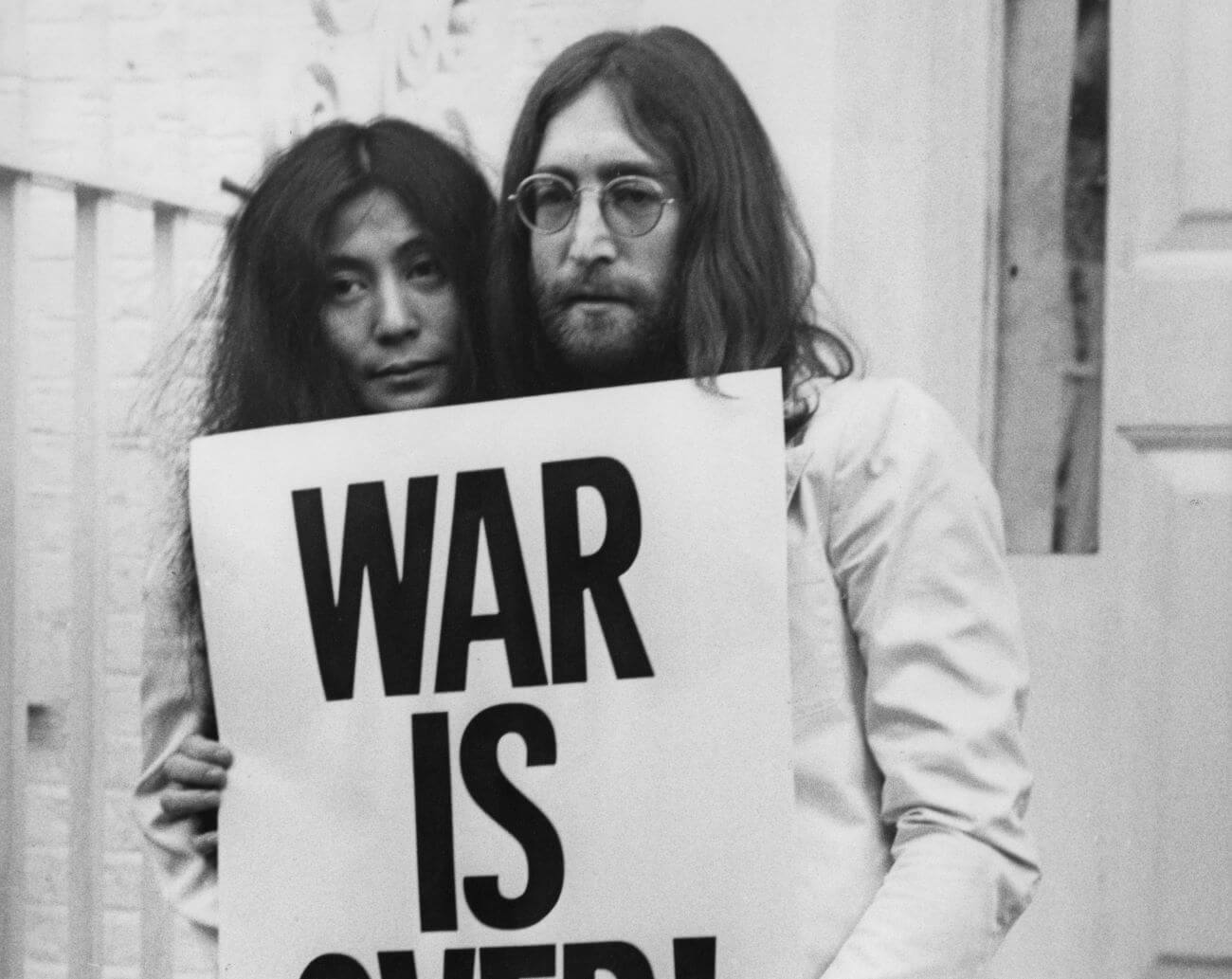 A black and white picture of Yoko Ono and John Lennon holding a poster that says "War Is Over."