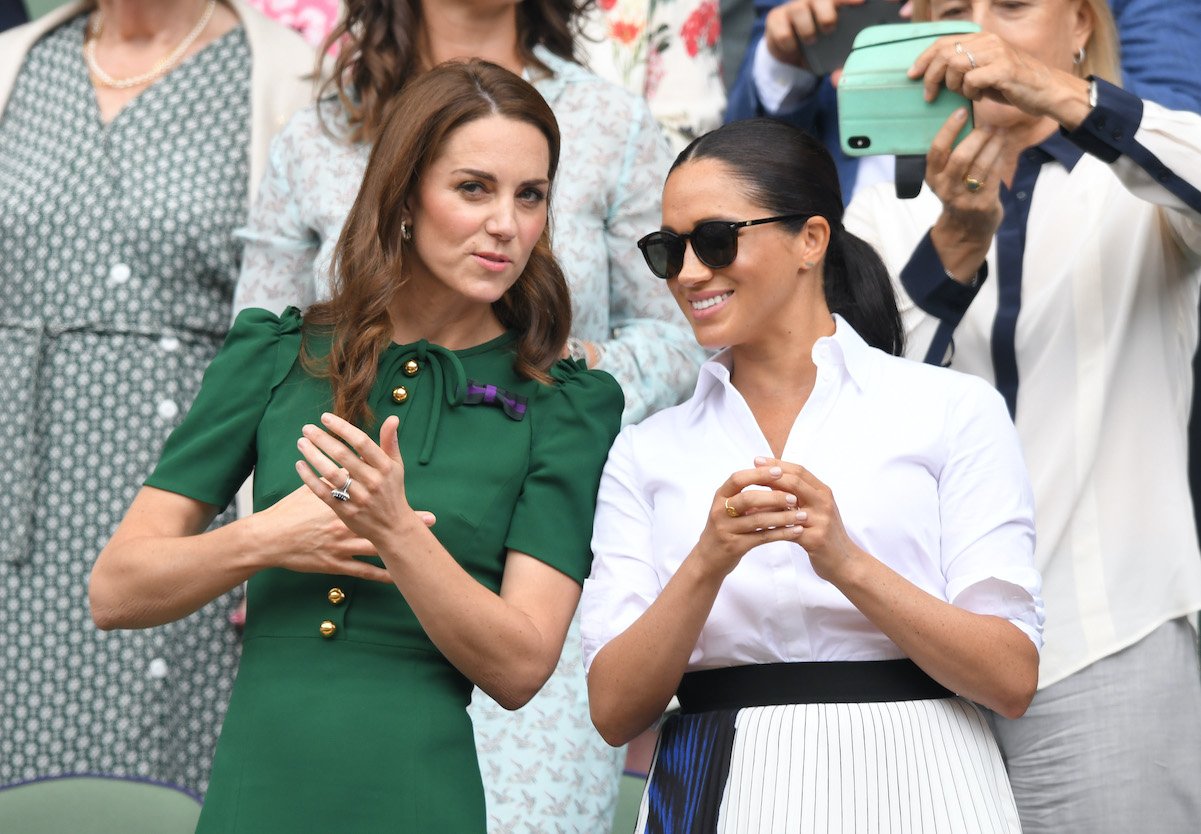 Kate Middleton and Meghan Markle stand and chat at Wimbledon in 2019