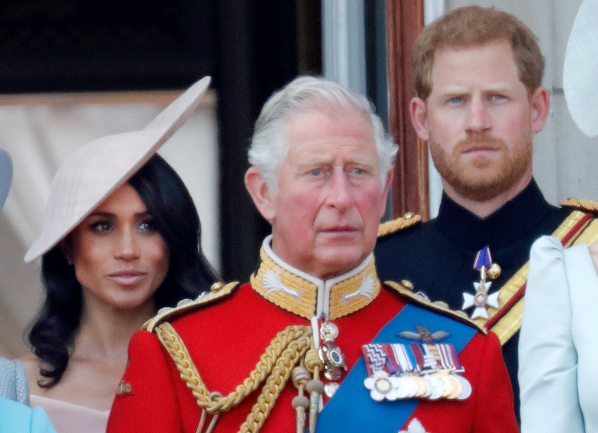 King Charles stands in front of Meghan Markle and Prince Harry