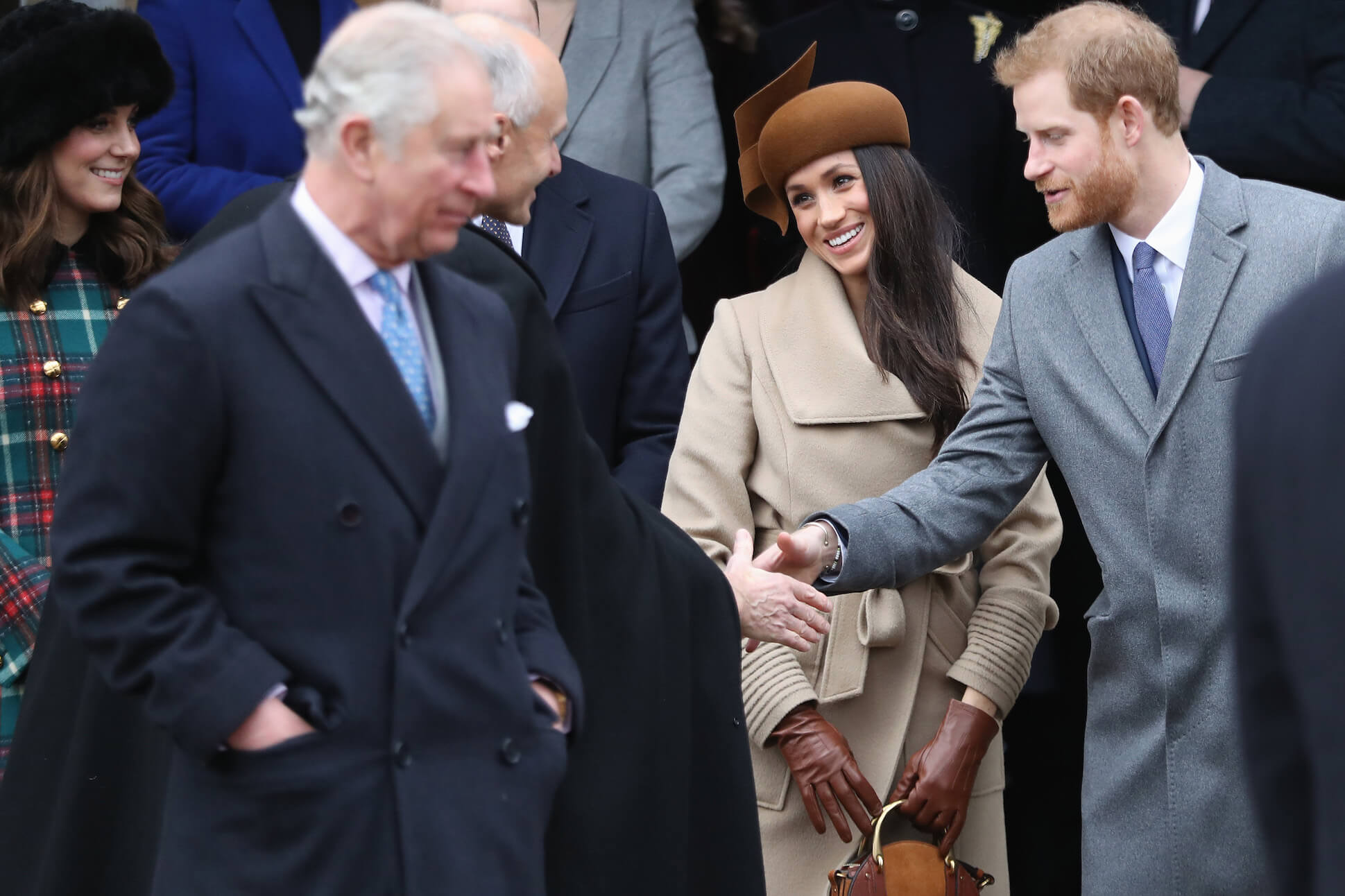 Meghan Markle and Prince Harry smiling while King Charles looks on