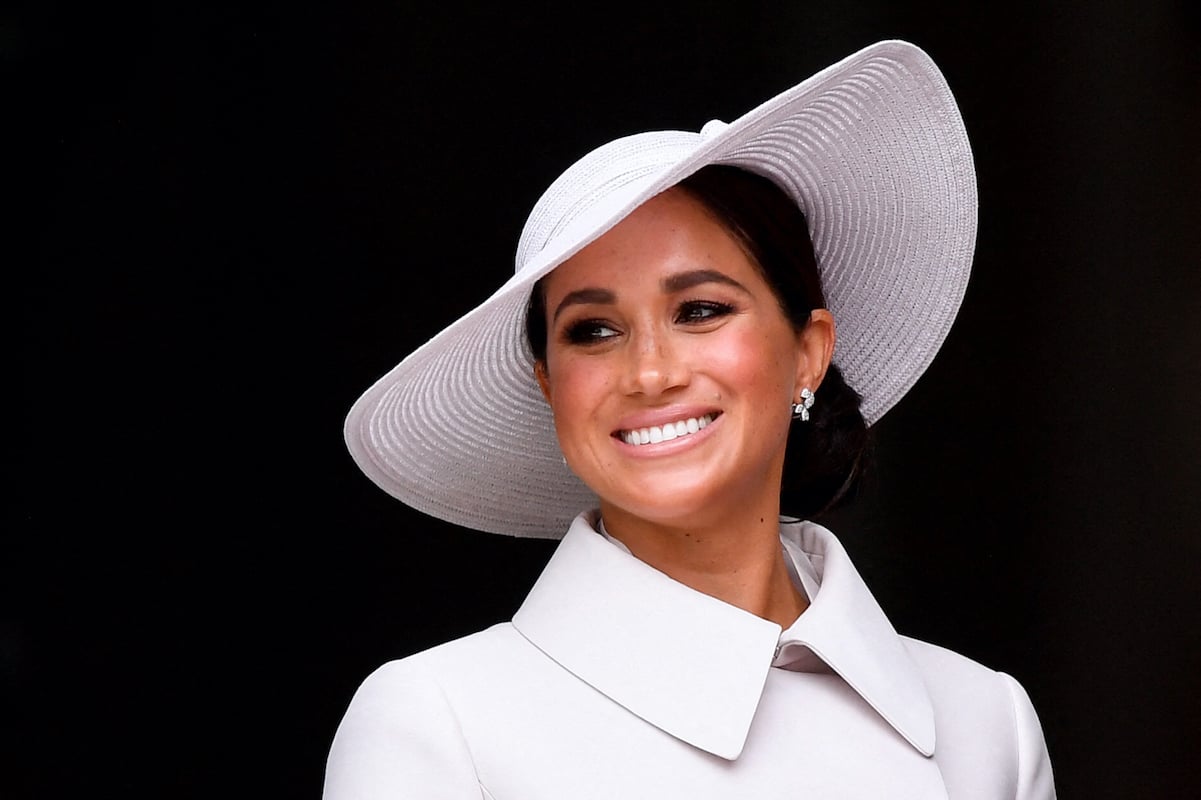 Meghan Markle smiles wearing white outfit