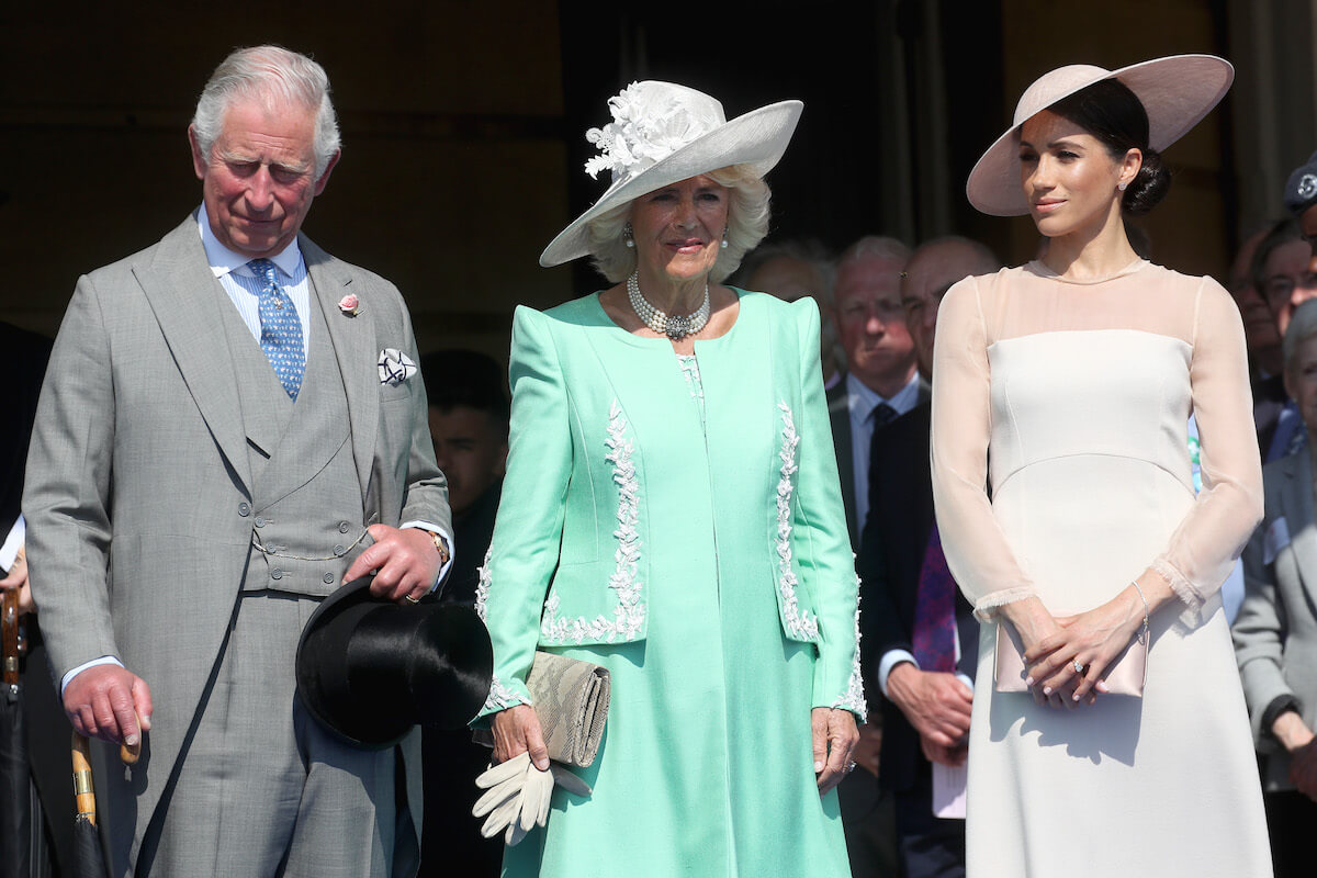 Meghan Markle, who responded to a report regarding a letter to King Charles and her coronation absence, stands with King Charles and Camilla Parker Bowles