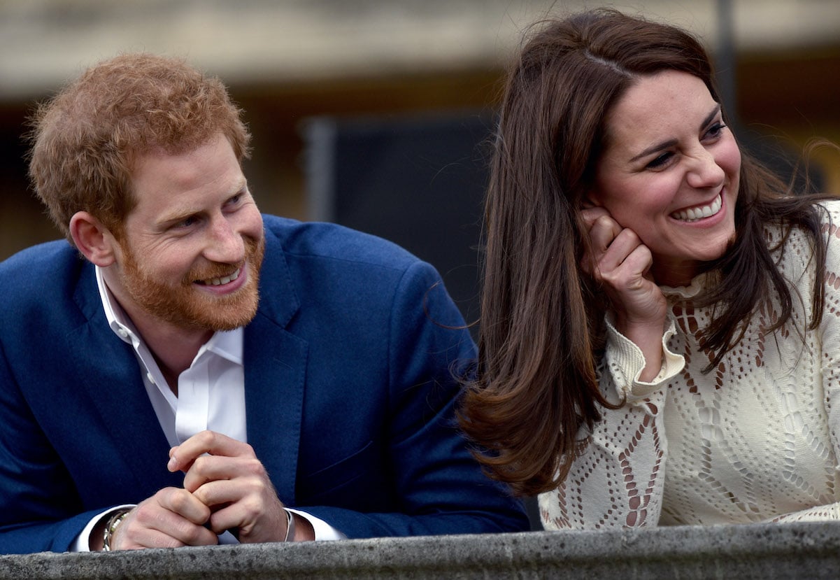 Kate Middleton and Prince Harry smile while looking to their left in 2017