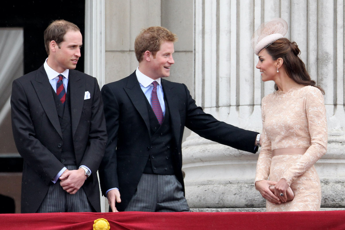 Prince Harry touches Kate Middleton's arm while standing next to Prince William