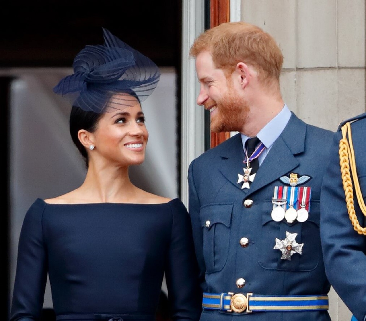 Prince Harry and Meghan Markle, who an author believes is "furious" over balcony snub at the coronation, standing on the balcony of Buckingham Palace for a flypast