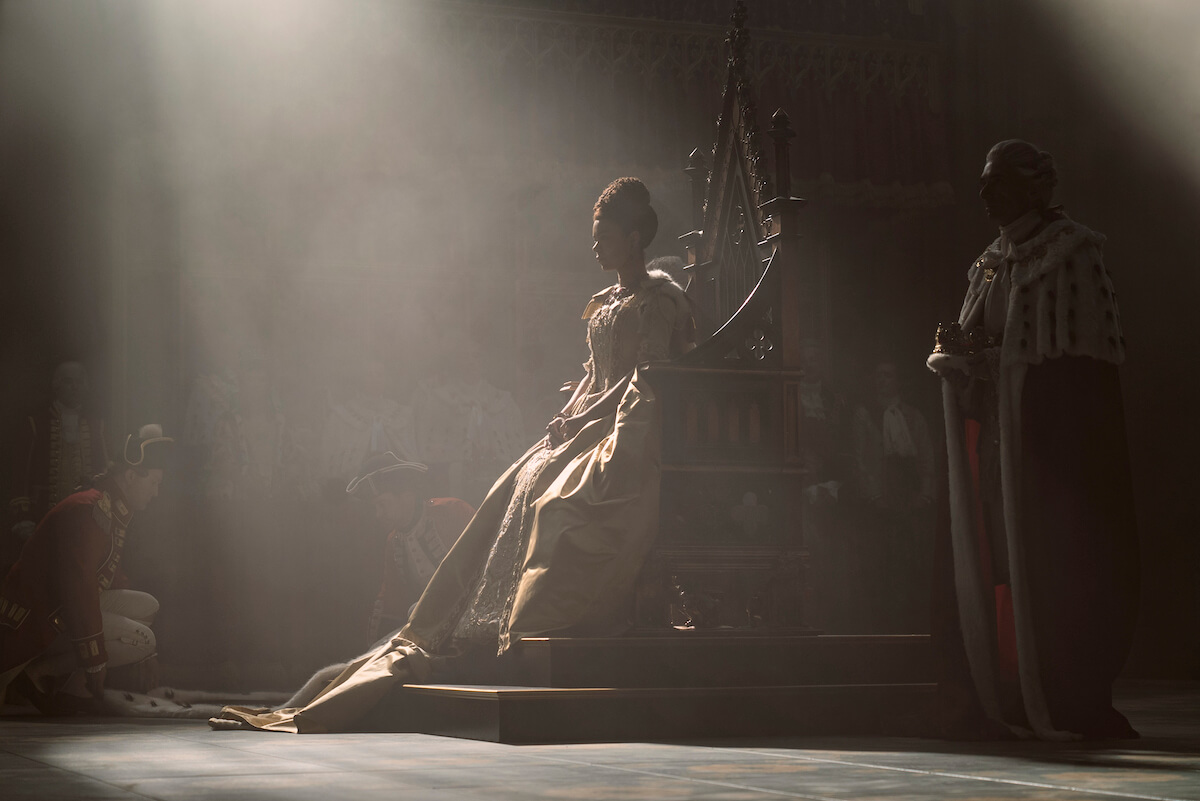 India Amarteifio as Queen Charlotte sitting on a throne in the dark in 'Queen Charlotte: A Bridgerton Story'