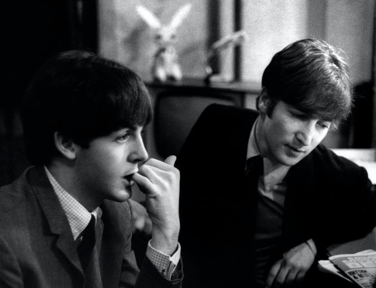 Paul McCartney and John Lennon sitting together in late 1963.