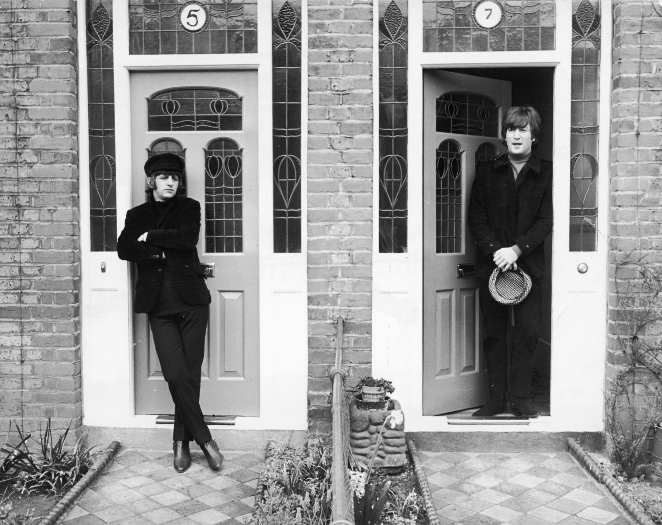 A black and white picture of Ringo Starr and John Lennon standing in doorways next to each other.