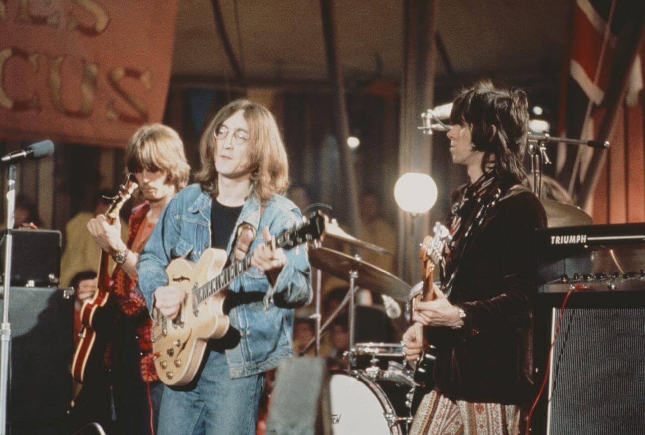 John and Keith Richards stand together on a stage and play guitars.