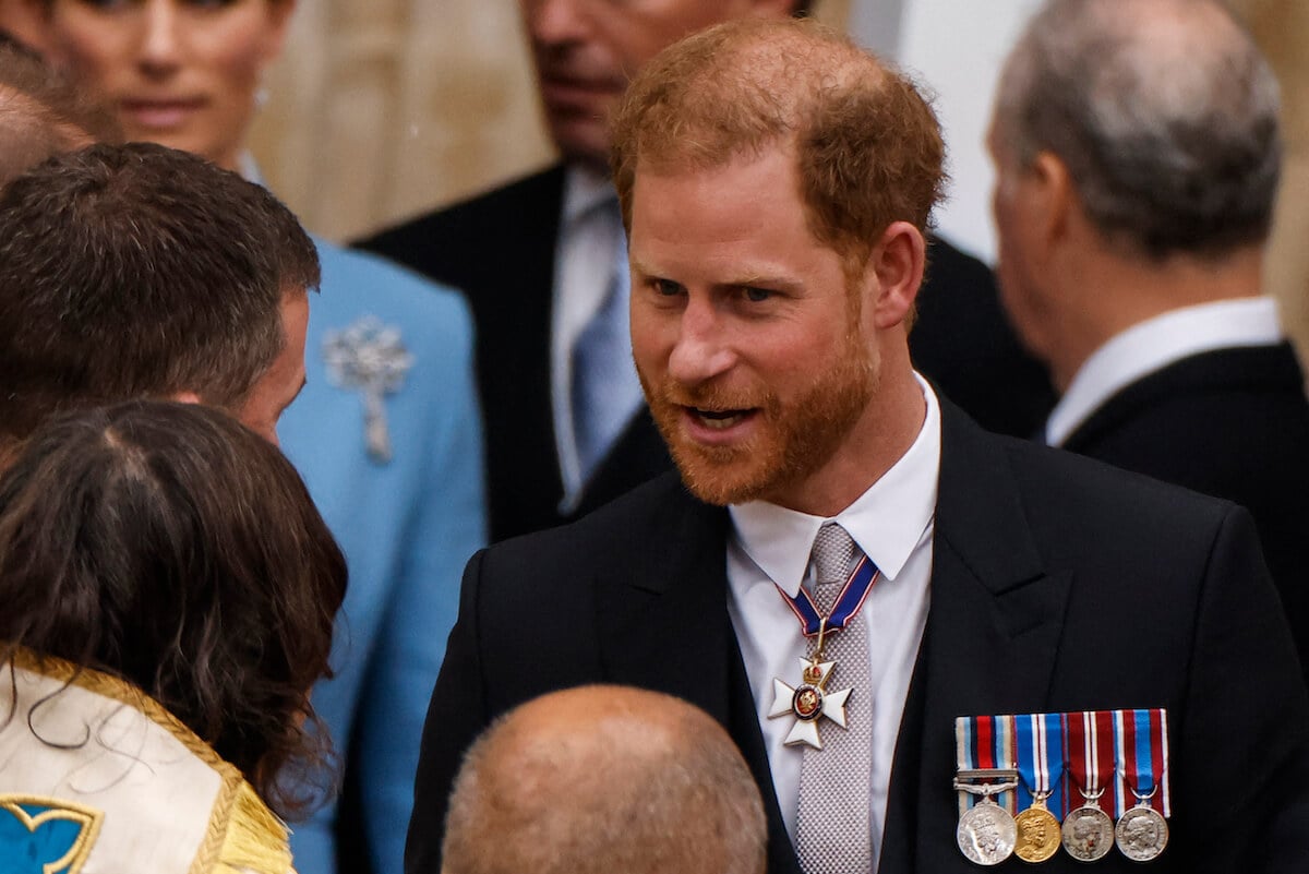 Prince Harry, who has questions to ask before his U.K. return, looks on at the coronation