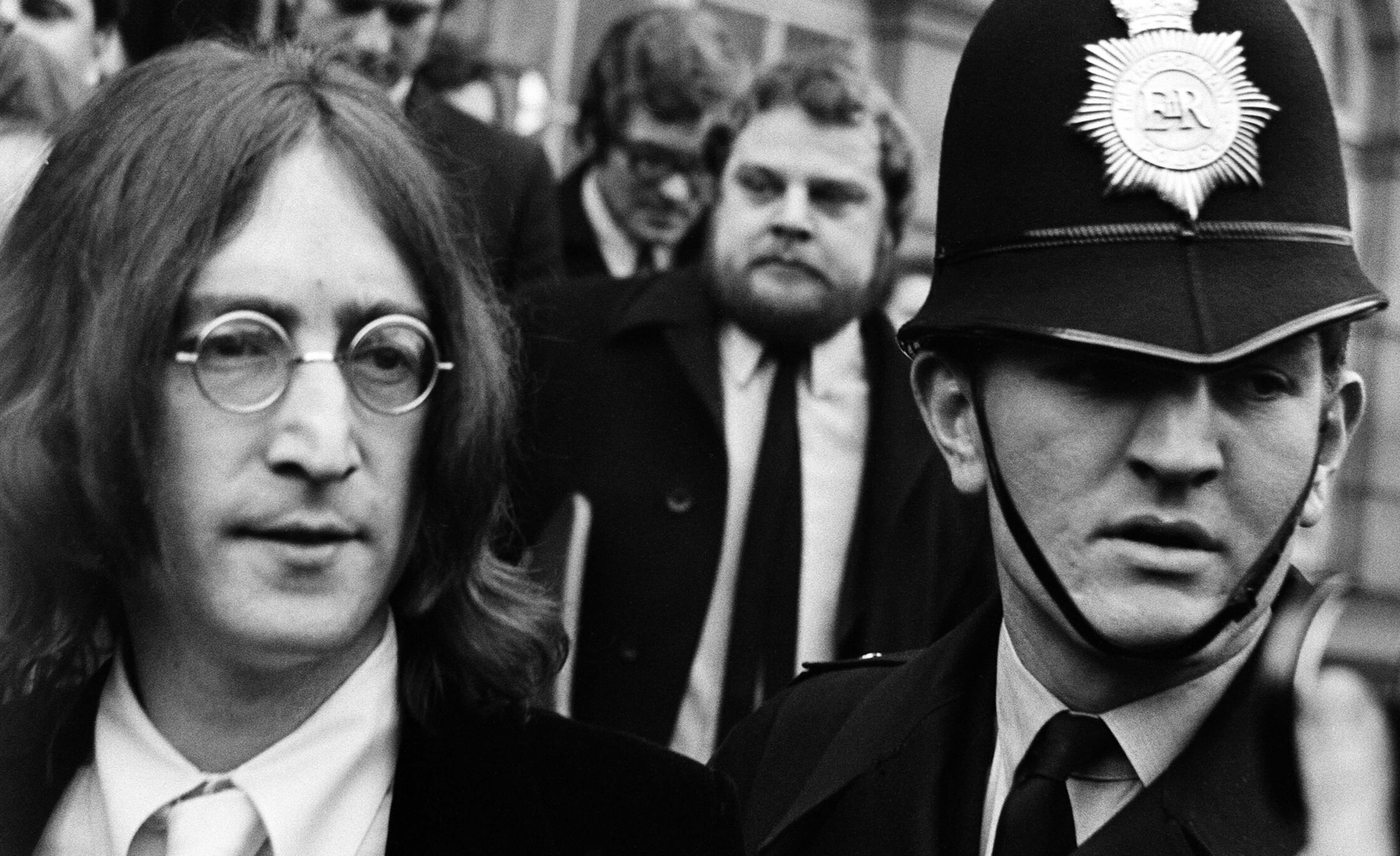 A black-and-white picture of The Beatles' John Lennon near a police officer