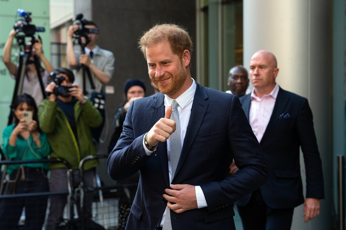 Prince Harry, who a royal expert says is 'relieved' to miss Trooping the Colour this year, gives a thumbs up as he leaves London courtroom