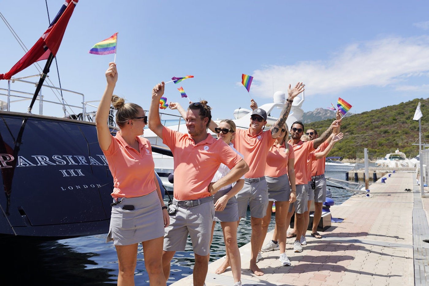 Daisy Kelliher, Gary King, Ileisha Dell, Chase Lemacks, Colin Macrae, Alex Propson from 'Below Deck Sailing Yacht' wave Pride flags