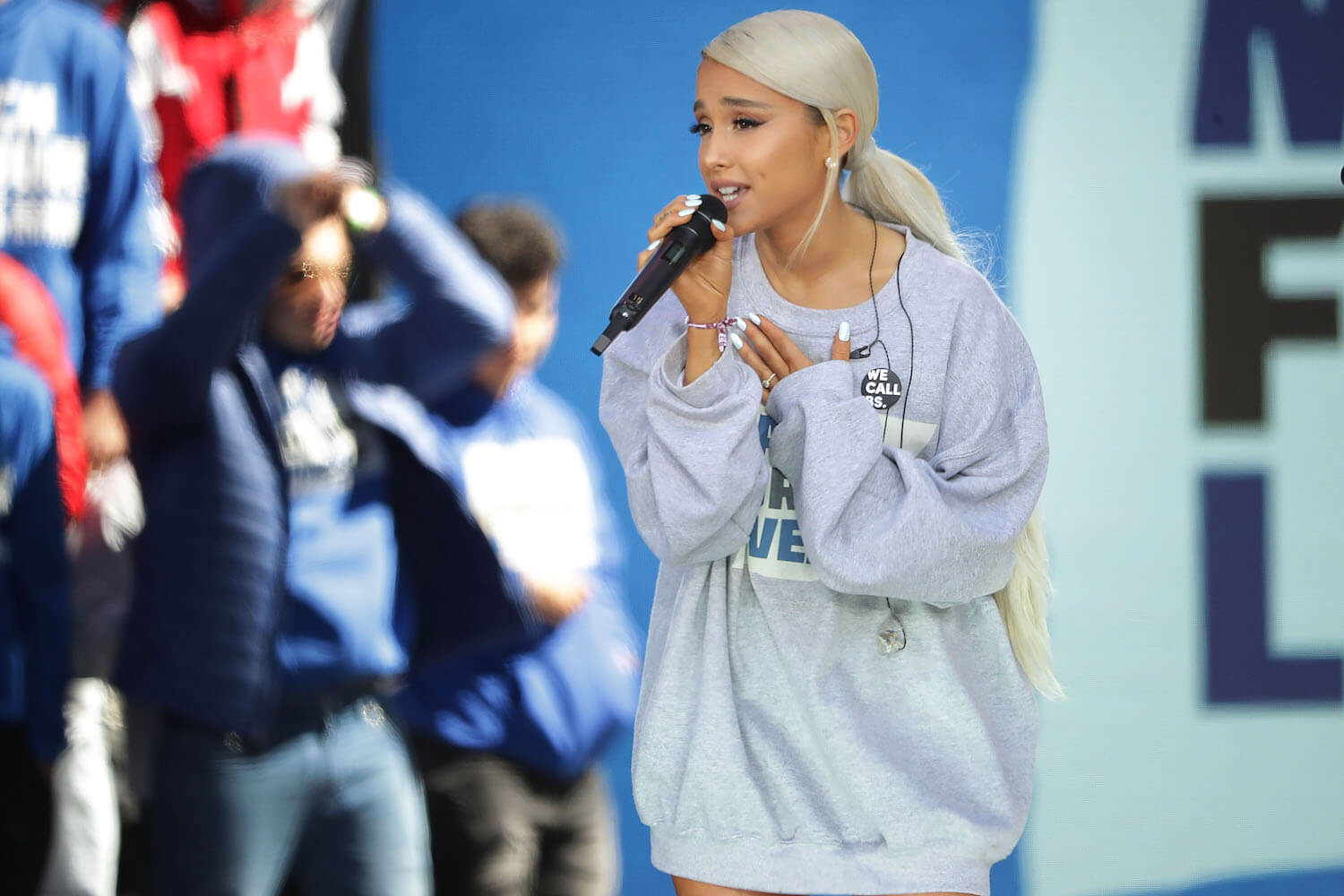 Ariana Grande singing into a microphone on an outdoor stage