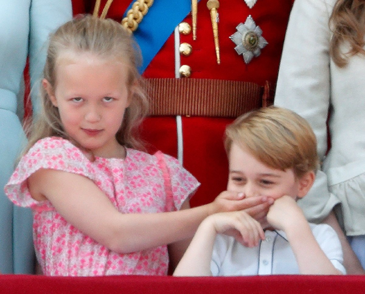 Savannah Phillips puts her hand over Prince George's mouth whilst they stand on the balcony of Buckingham Palace during Trooping The Colour