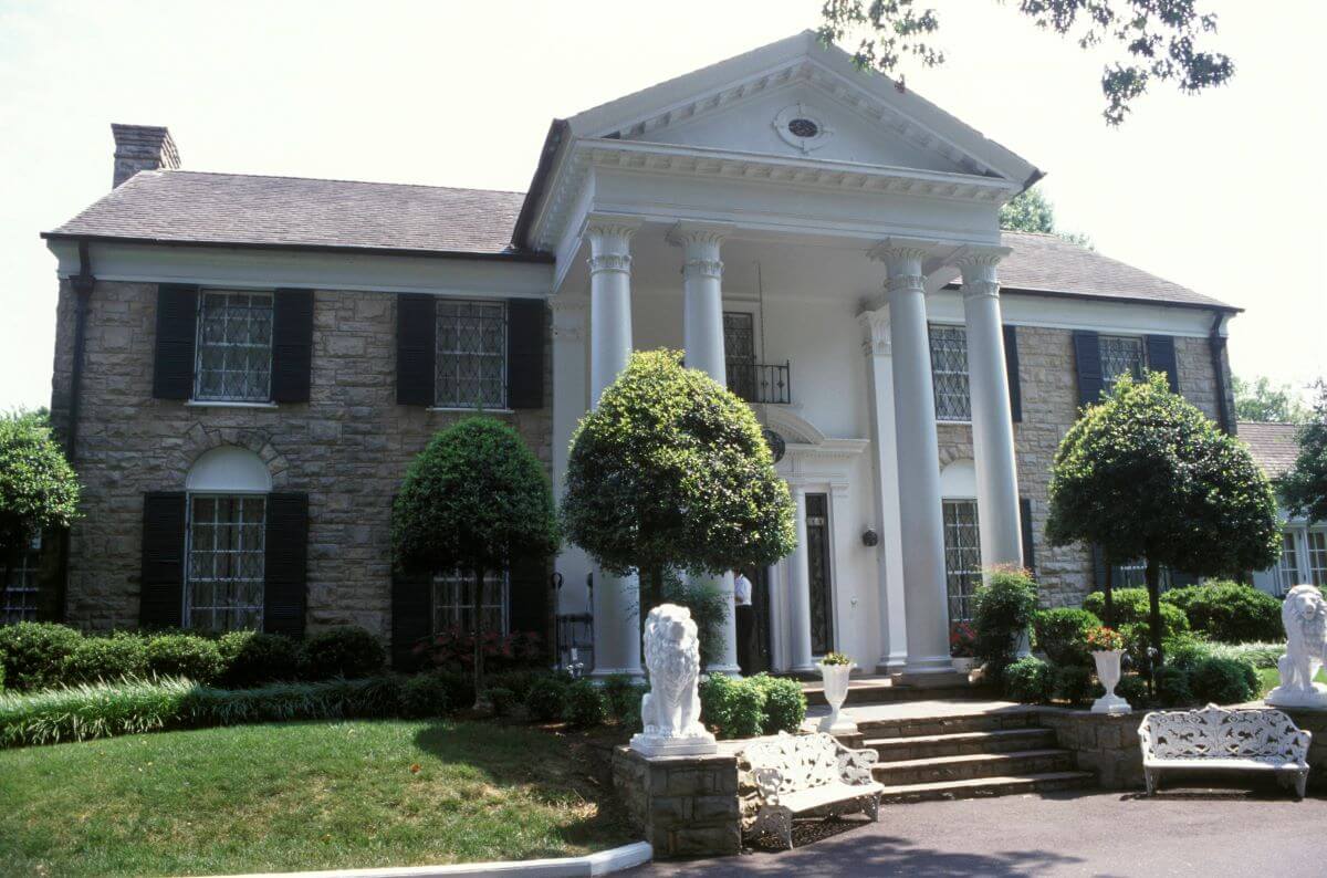 The front of Elvis' home Graceland has a  bench and a lion statue on either side of the steps up to the front door.