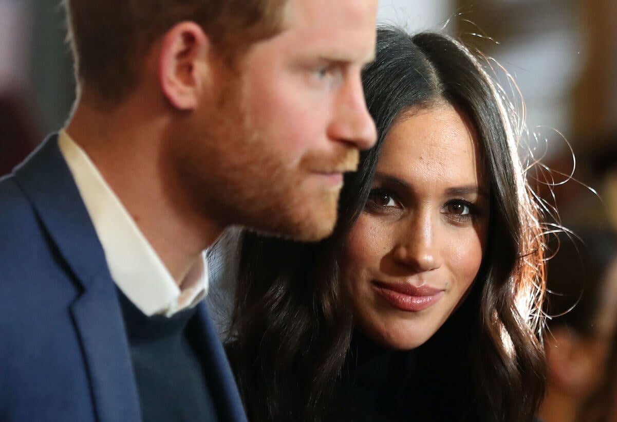 Meghan Markle looks into the camera while standing next to Prince Harry