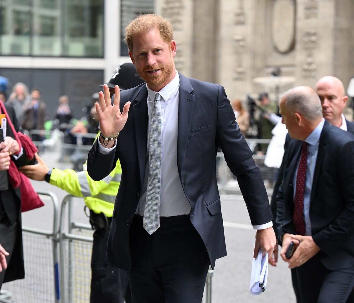 Prince Harry, whose body language was analyzed during his trip to Tokyo without Meghan, waving as he arrives at the Rolls Building at High Court in London