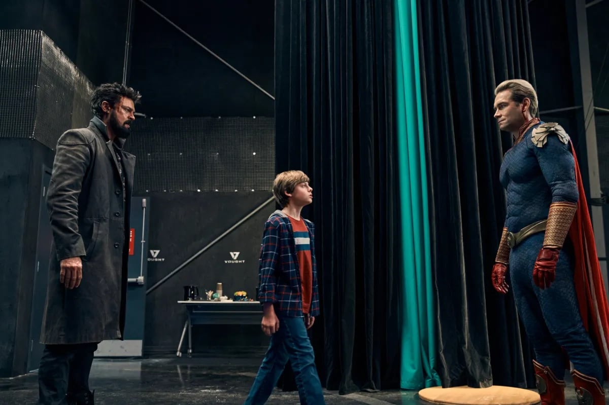 A photo of Antony Starr's Homelander facing off against Karl Urban's Butcher with Cameron Crovetti's Ryan between them.