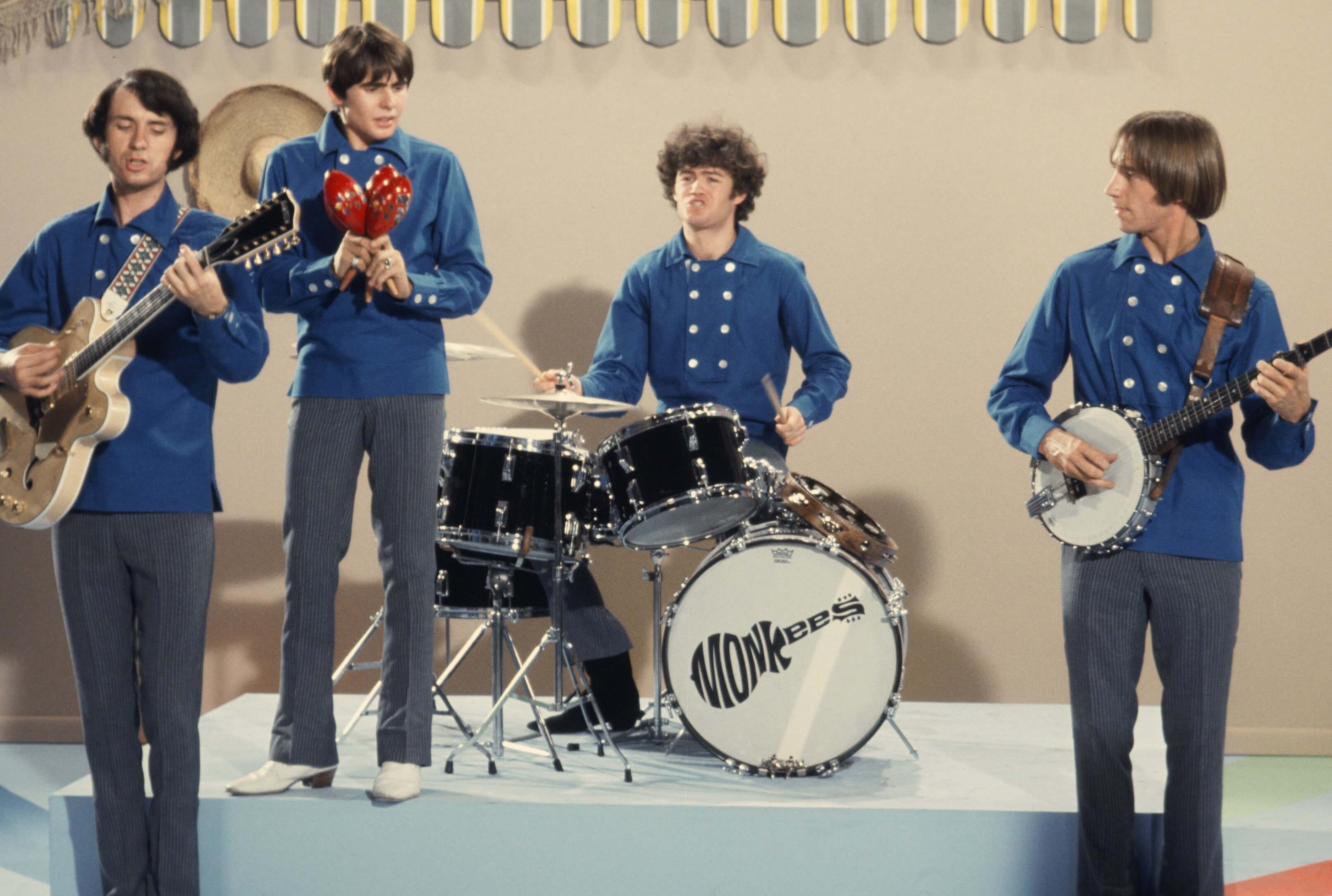 The Monkees wearing blue and playing instruments