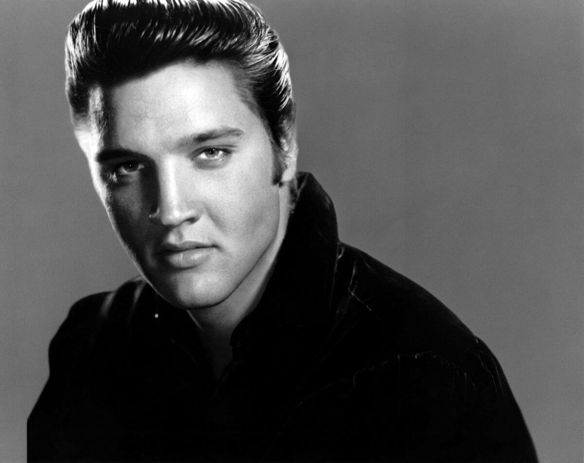 A black and white picture of Elvis wearing a jacket.