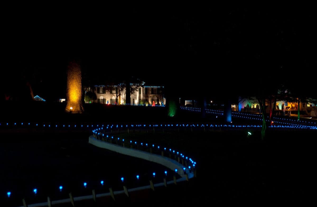 A photo of Graceland and the drive up to it lit up with Christmas lights. It is night.