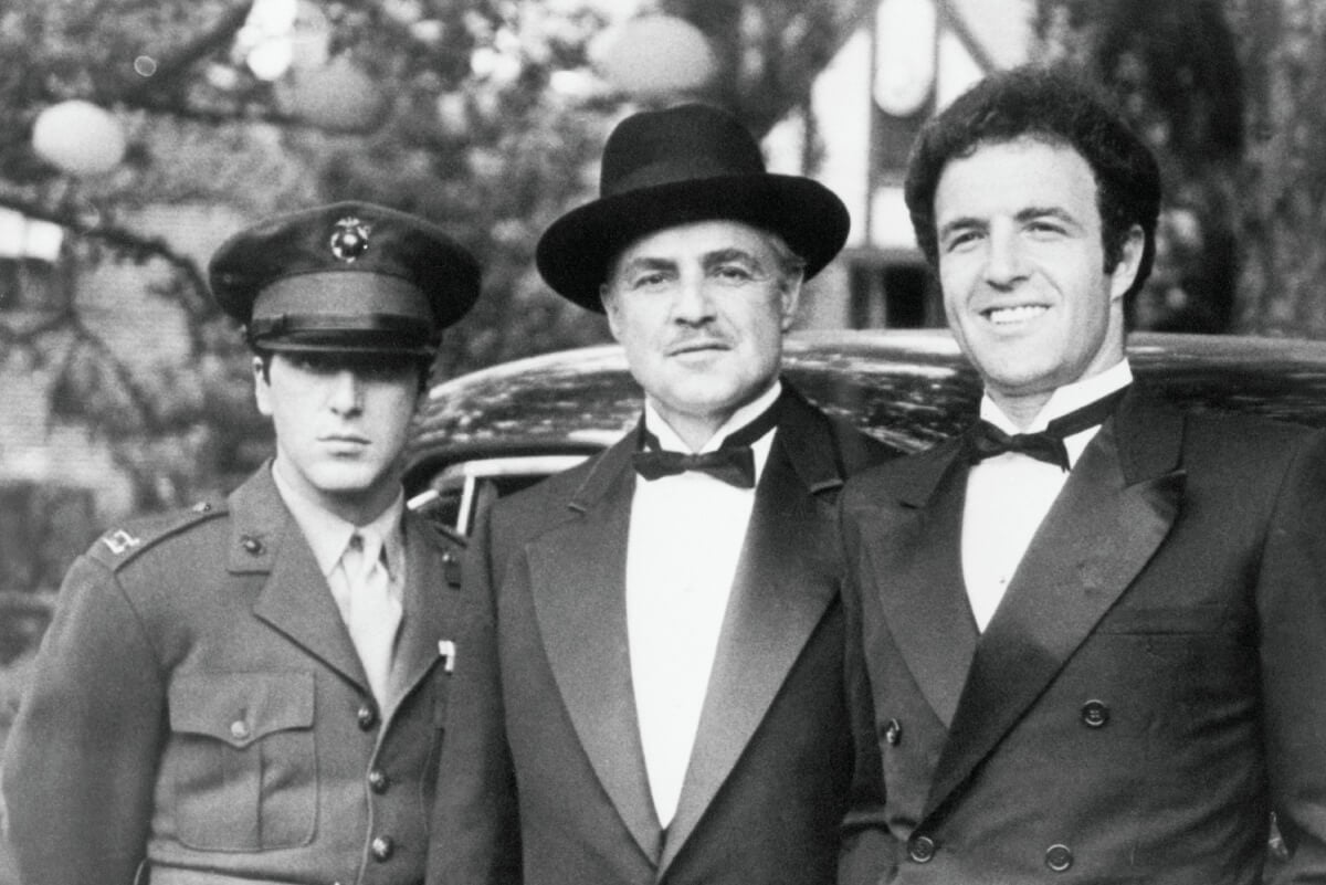 Al Pacino (as younger son Michael Corleone), Marlon Brando (as father Vito Corleone) and James Caan (as eldest son Sonny Corleone), in costume for the opening scene of The Godfather