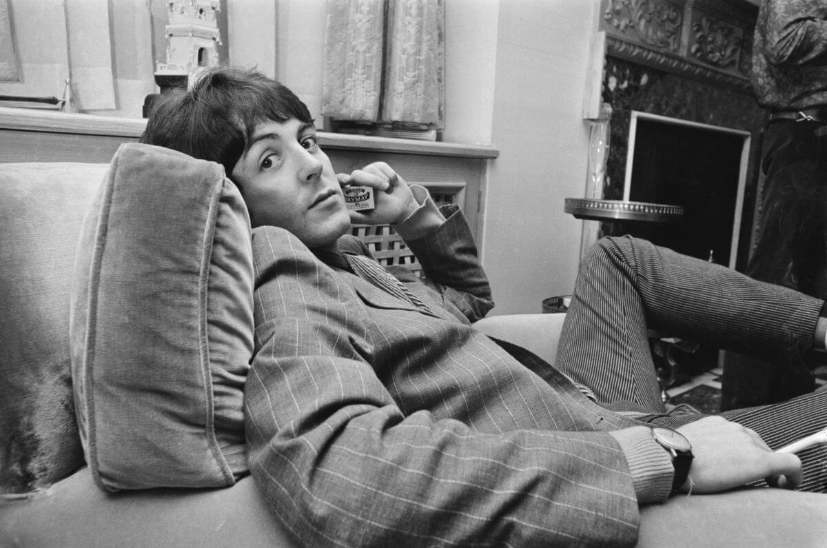 A black and white picture of Paul McCartney sitting in an arm chair and holding a matchbox.