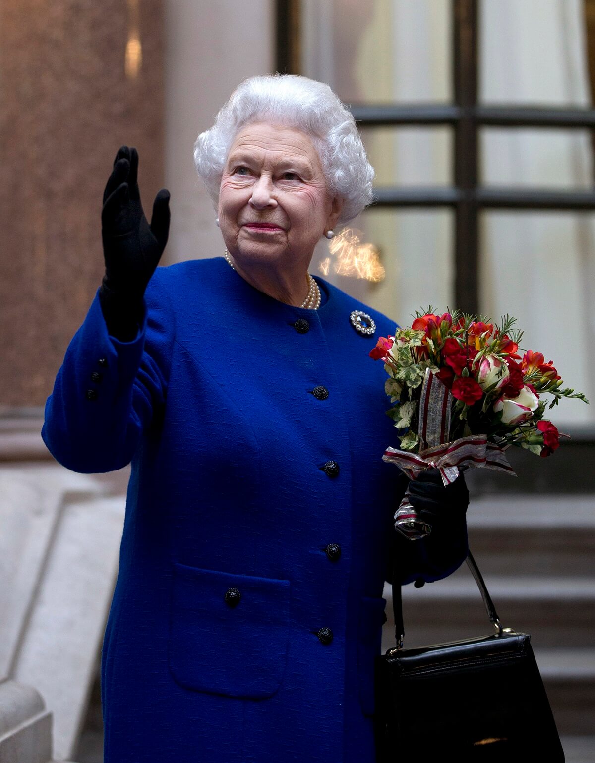 Queen Elizabeth II looks up and waves to members of staff of The Foreign and Commonwealth Office