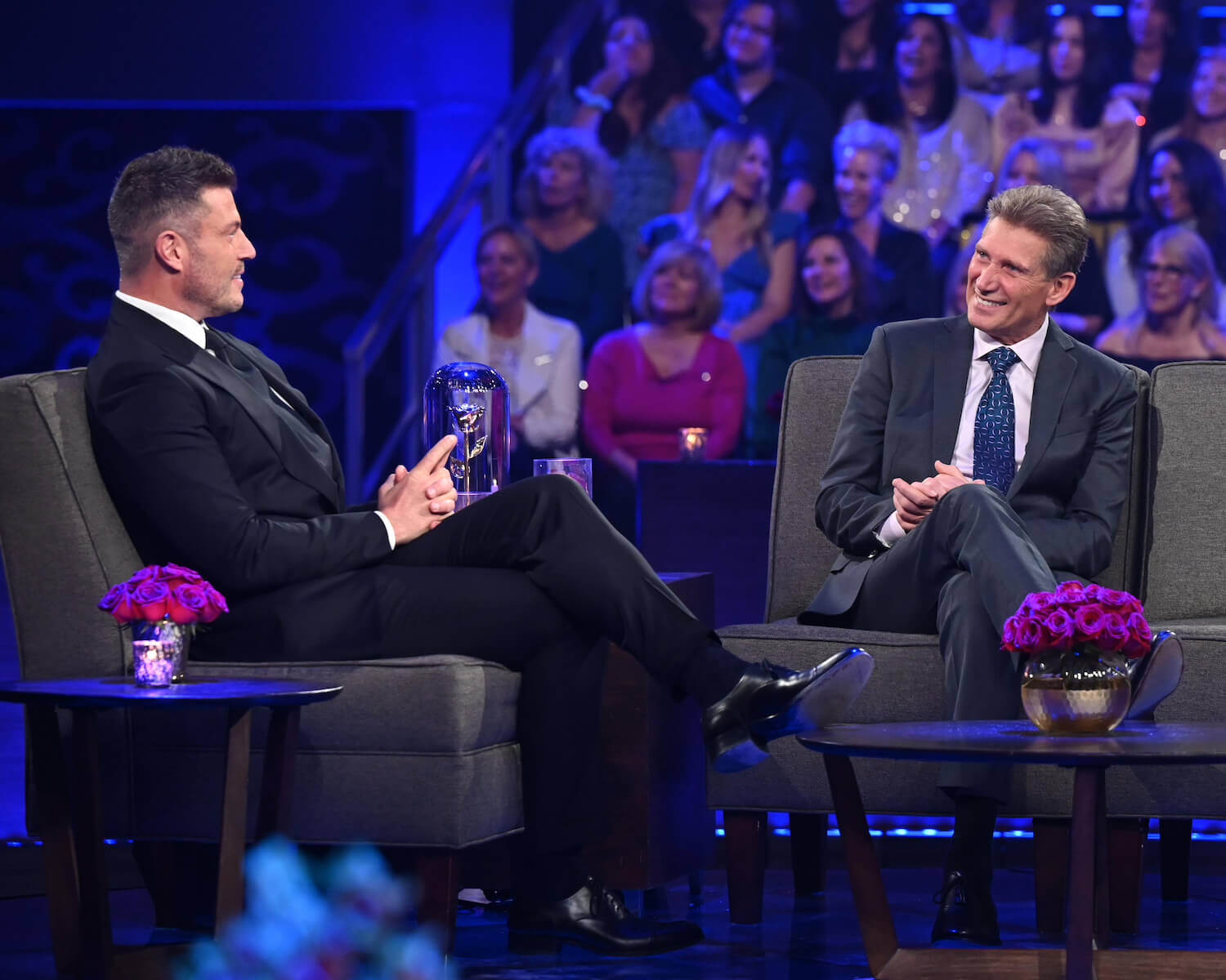 Jesse Palmer sitting on stage with 'The Golden Bachelor' star Gerry Turner