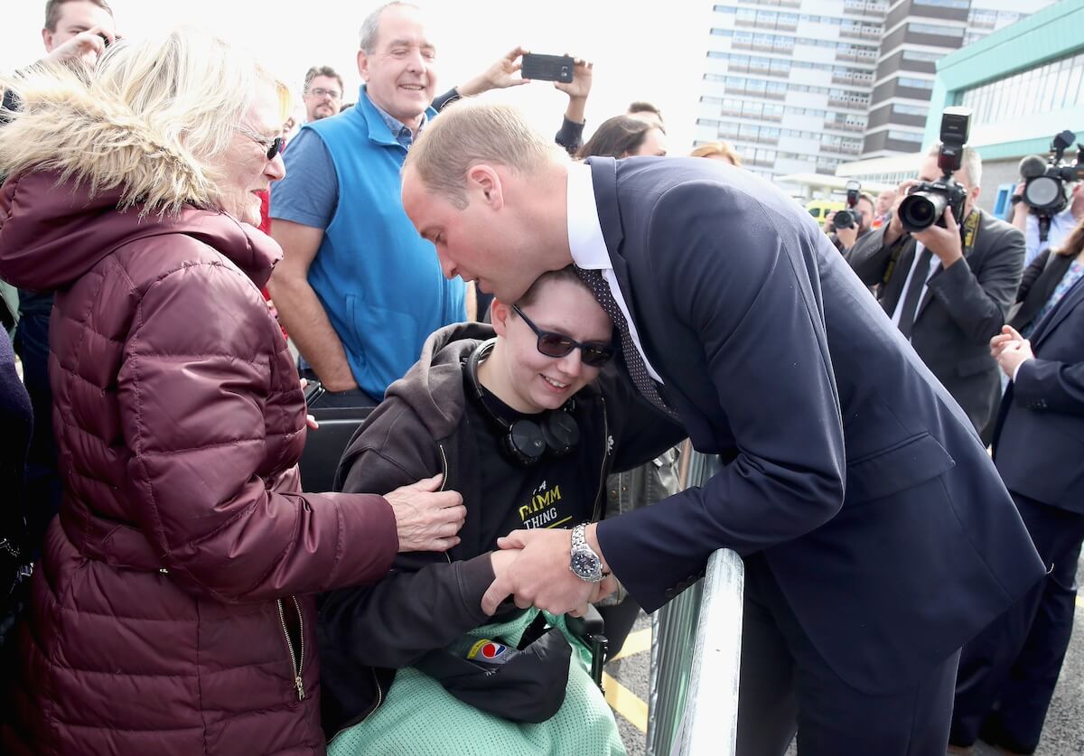 Prince William hugs a child during a royal event