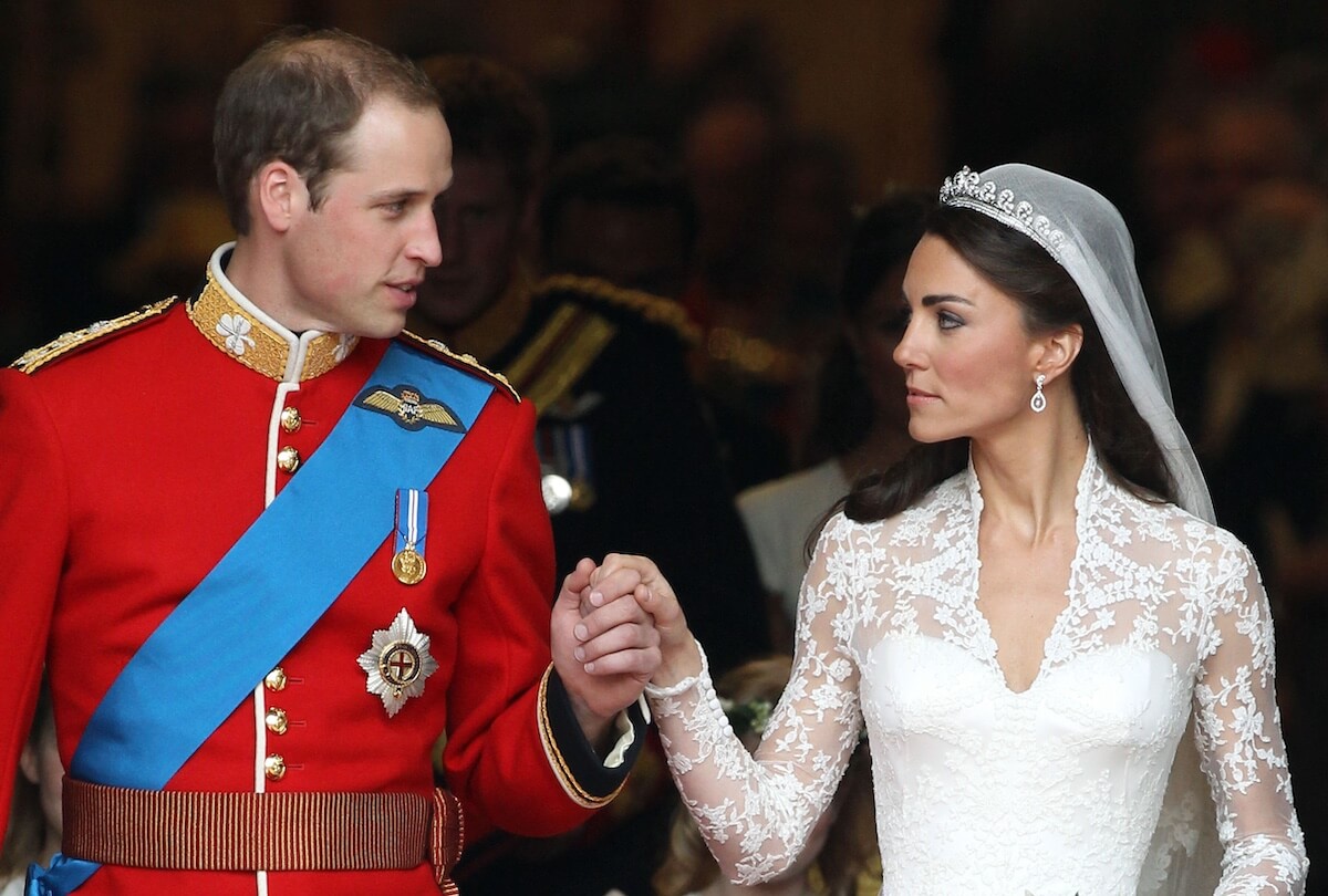 Prince William, whose wedding band is noticeably absent, holds hands with Kate Middleton