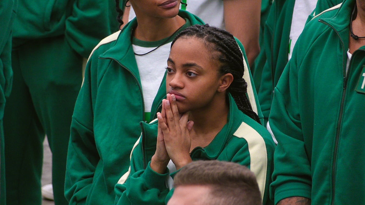 'Squid Game: The Challenge' contestant in a green jumpsuit with her hands in a prayer position