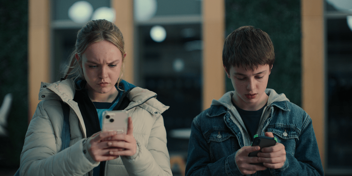 A boy and girl looking at the phones