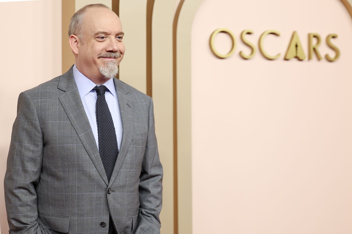 Paul Giamatti posing in a grey suit at Oscars luncheon.