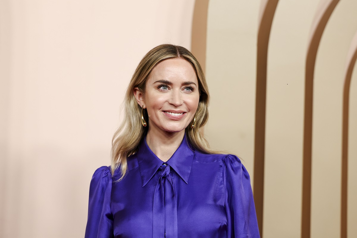 Emily Blunt posing at Oscars luncheon wearing a blue outfit.