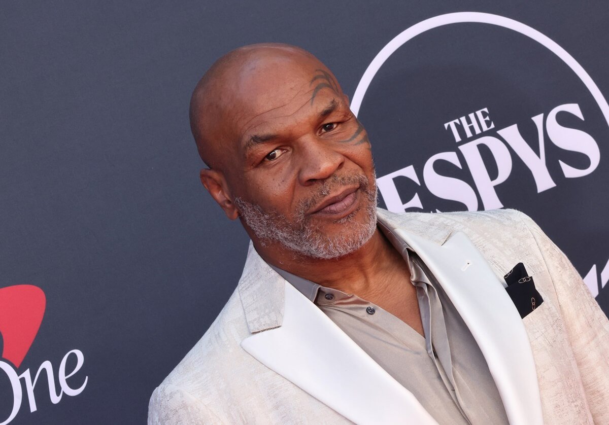 Mike Tyson posing at the Espys wearing a white and grey suit.