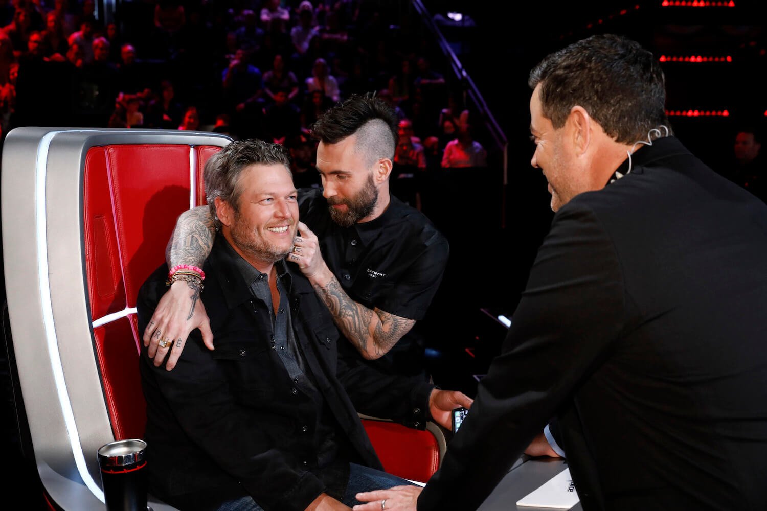 Adam Levine pinching Blake Shelton's cheek as Carson Daly leans into them on 'The Voice'